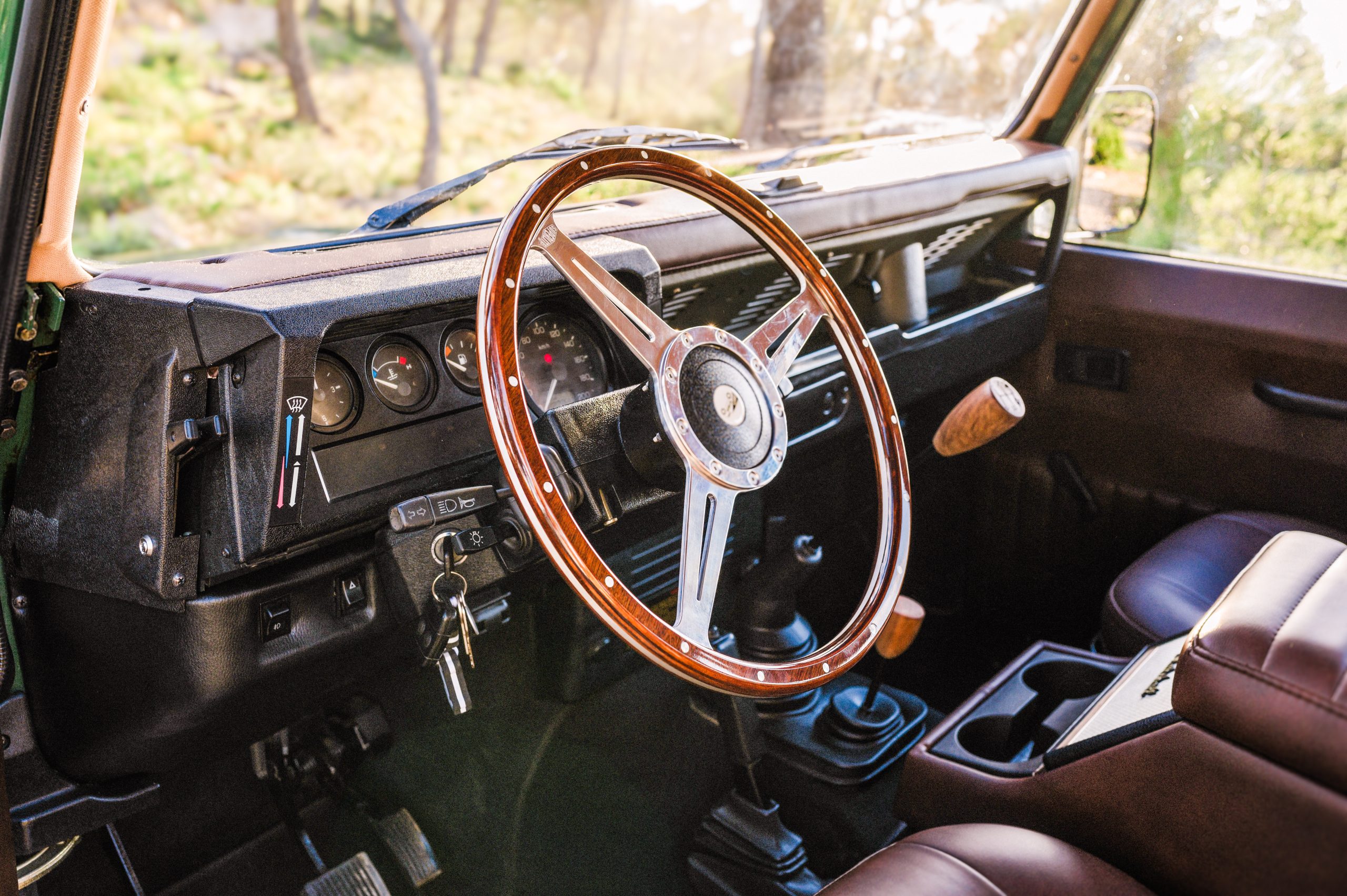 Classic Land Rover Defender interior with wooden steering wheel and leather seats