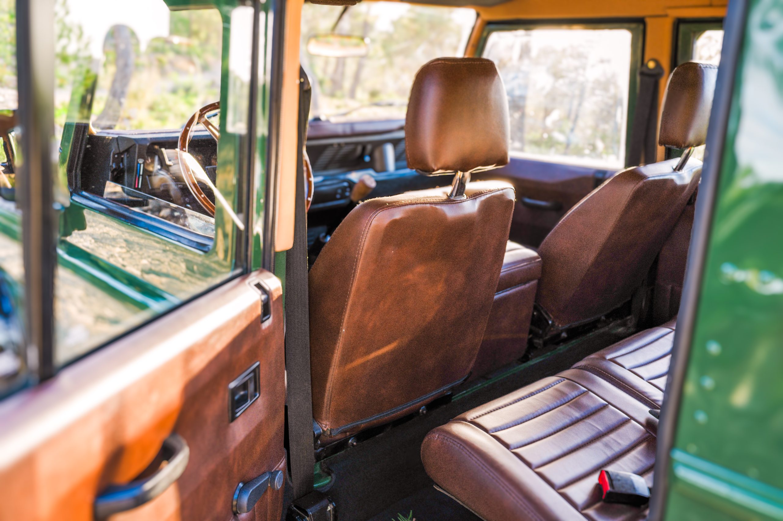 Restored Land Rover Defender interior with brown leather seats and rear bench seating